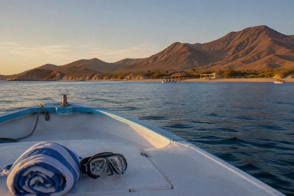 Small open tour boat cruising across calm morning water toward distant mountains