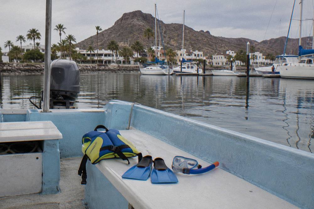 Snorkel gear and wetsuits laid out on a boat bench before a swim