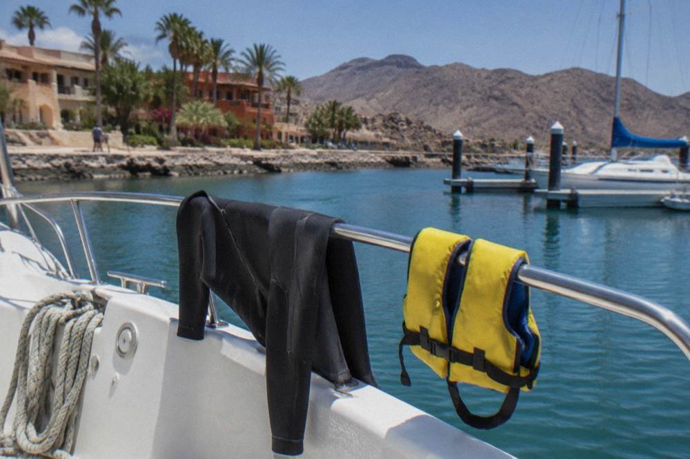 A wetsuit and life vest drying on a rail at the back of a tour boat