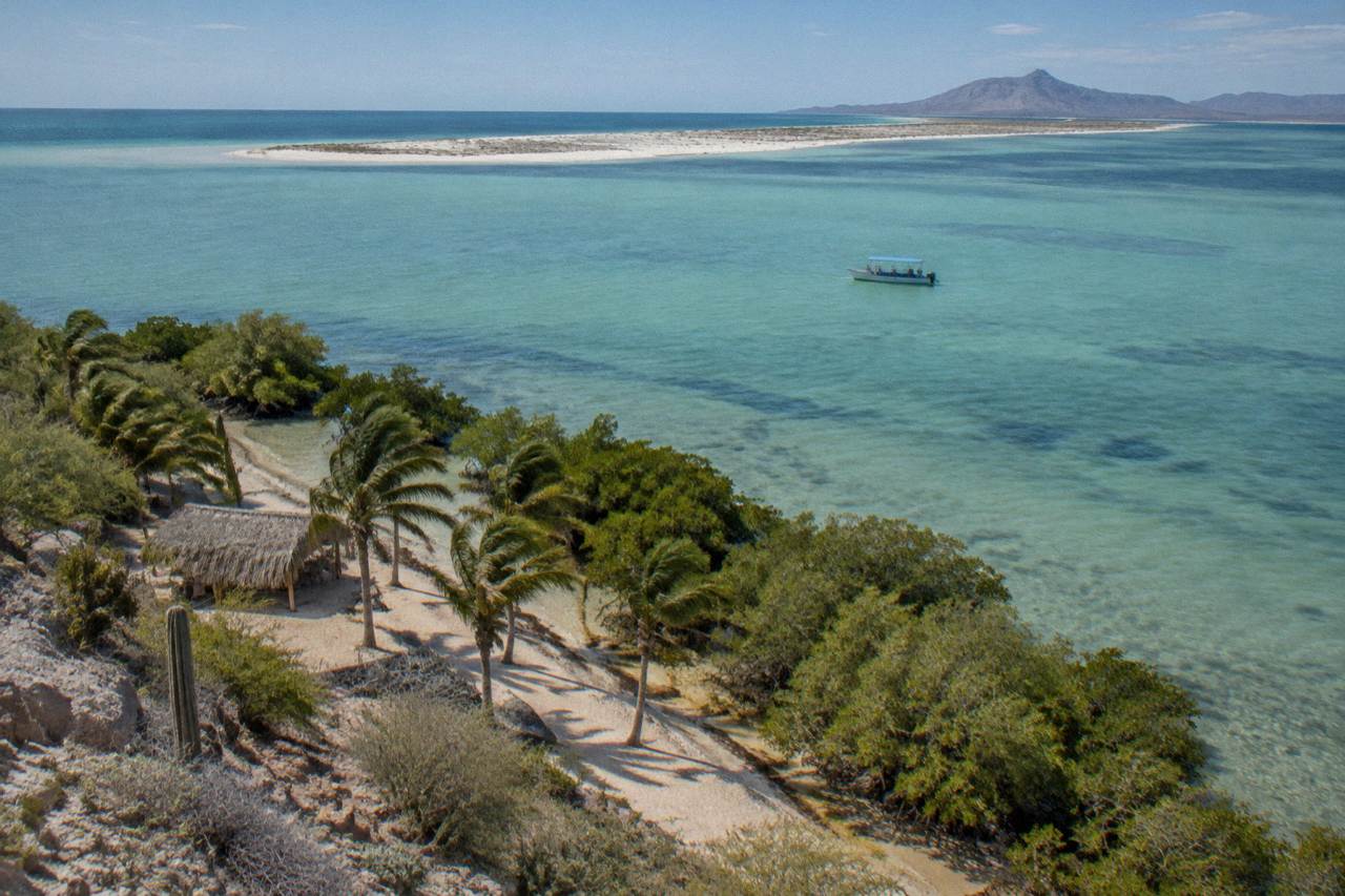 Calm turquoise water of a shallow bay near La Paz with a small boat in the distance