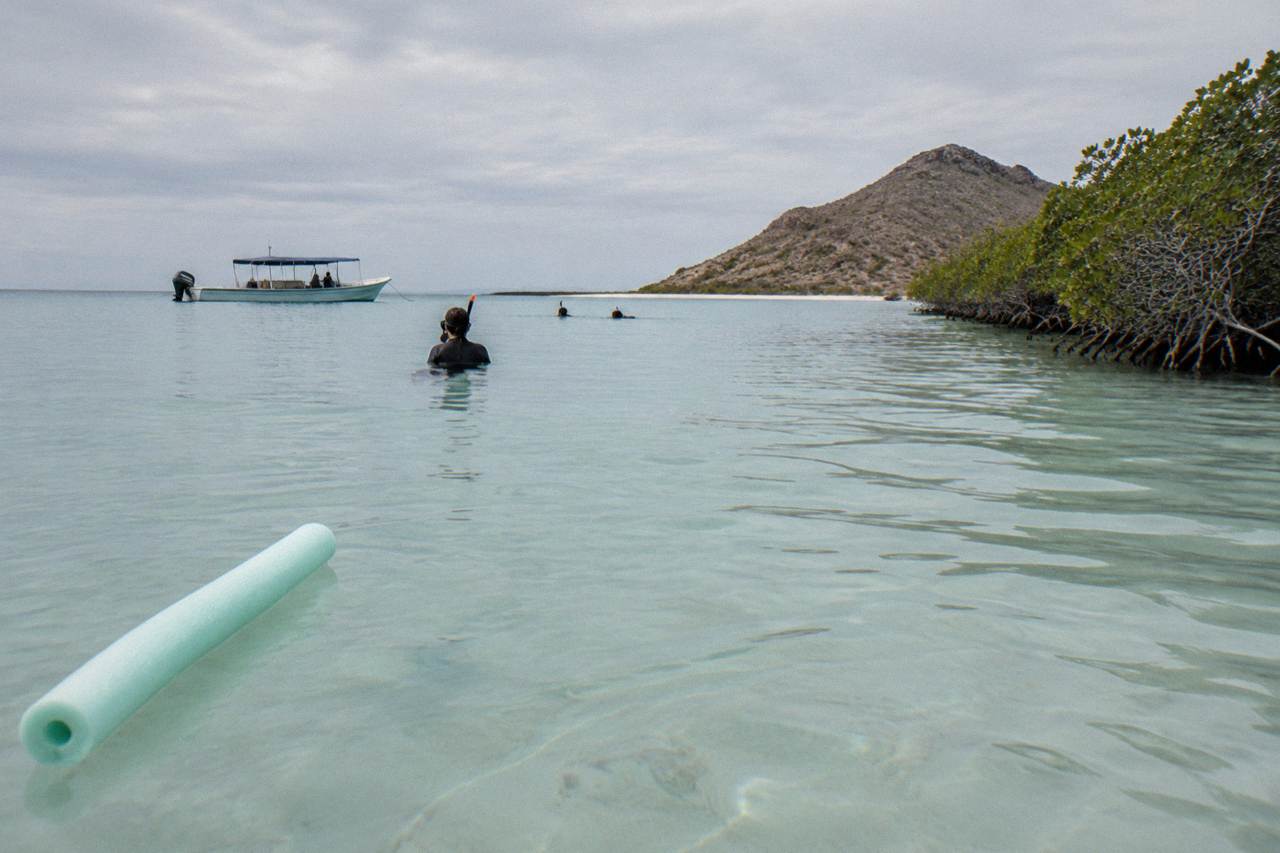 Calm shallow bay water near La Paz with a snorkel boat anchored in the distance