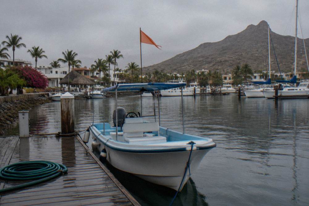 A small boat with a fluttering pennant flag moored at a marina dock