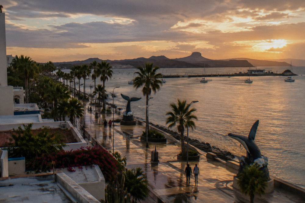 wide malecon walkway in La Paz at golden hour with the bay and distant hills beyond