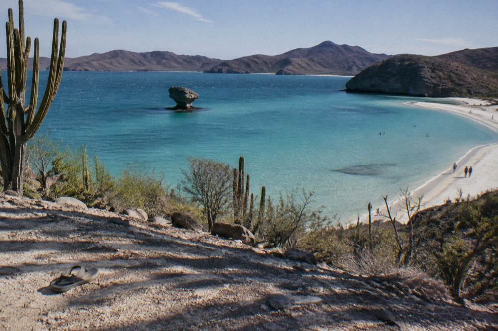 Wide shallow turquoise bay with a mushroom-shaped rock formation at one end