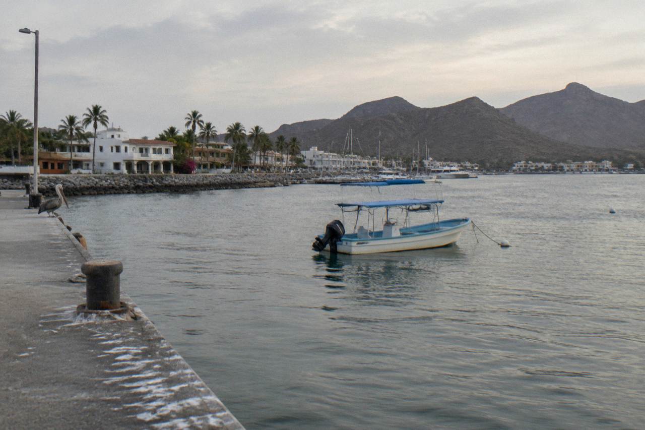 Calm bay water near La Paz with a snorkel boat at anchor under a pale morning sky