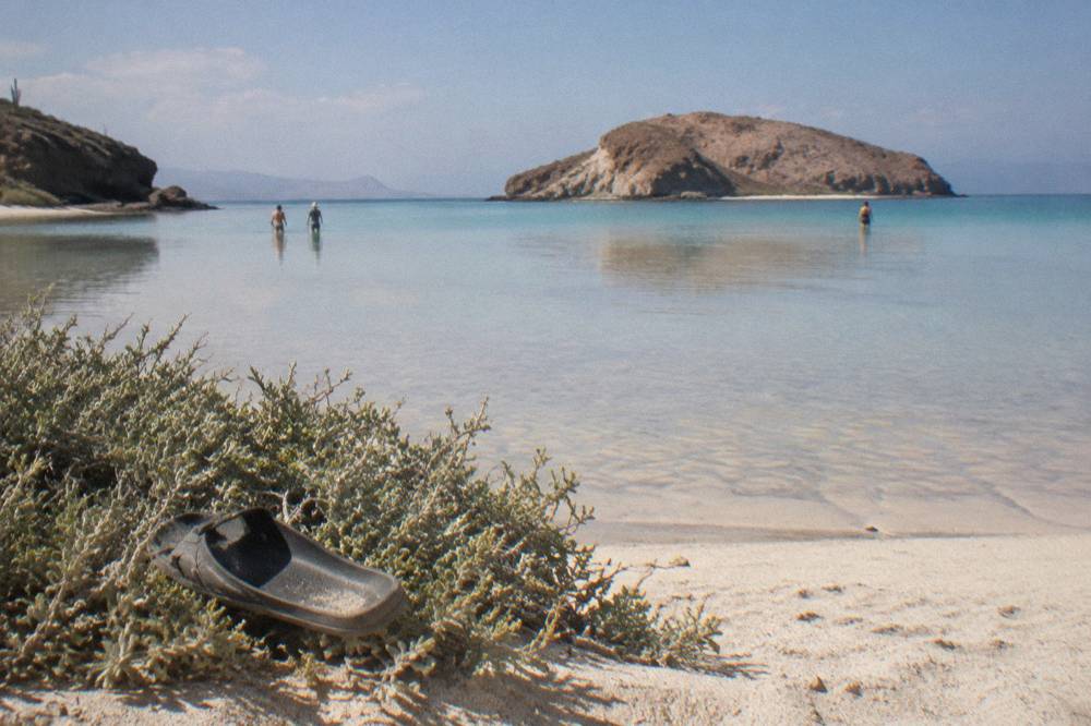 Shallow turquoise shallows of a protected beach with a rocky island beyond