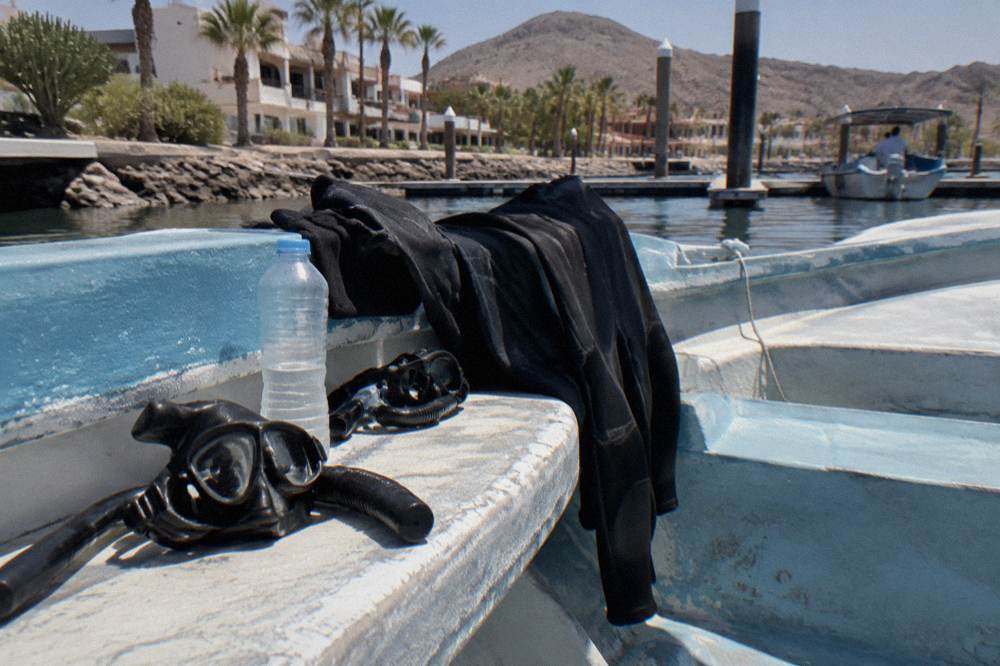 Snorkel masks and wetsuits laid out on a boat bench before a tour