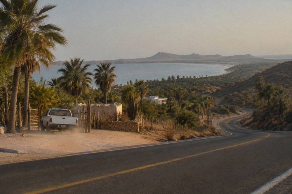 Coastal highway curving along dry hills toward a distant bay
