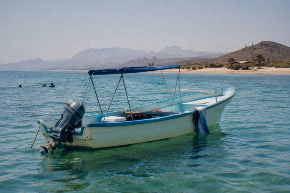 Small boat on calm blue bay water near La Paz with distant hills