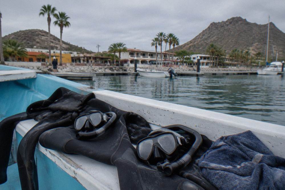 Wetsuits and snorkel masks laid out on a boat bench before departure
