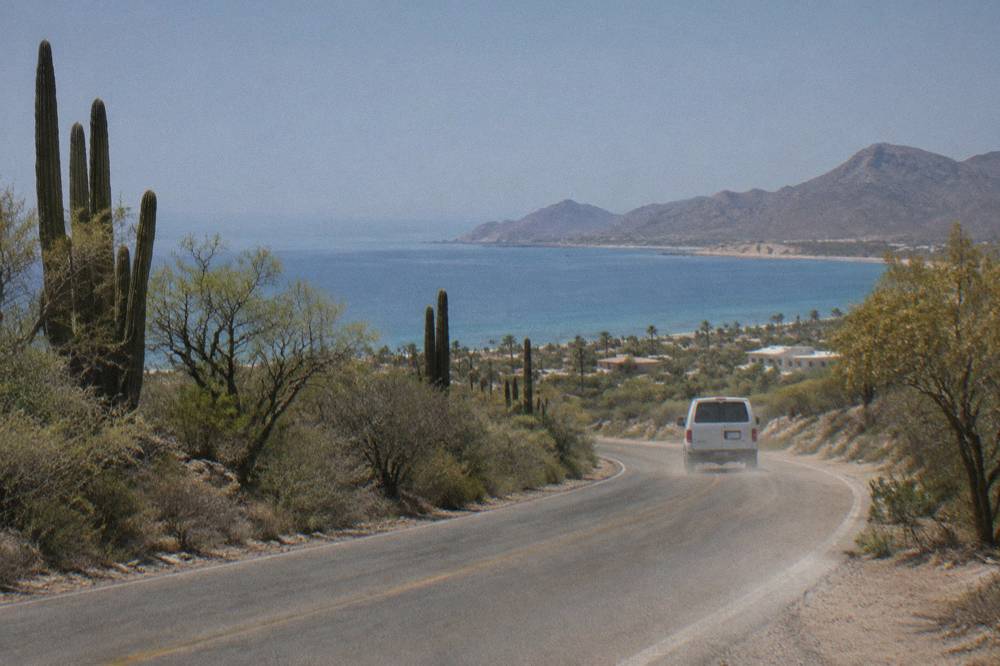 Coastal highway road winding between desert hills toward a bay