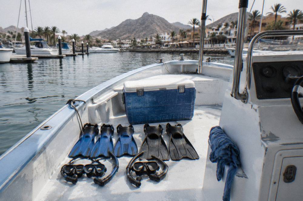Snorkel masks and fins arranged on a boat deck beside a cooler