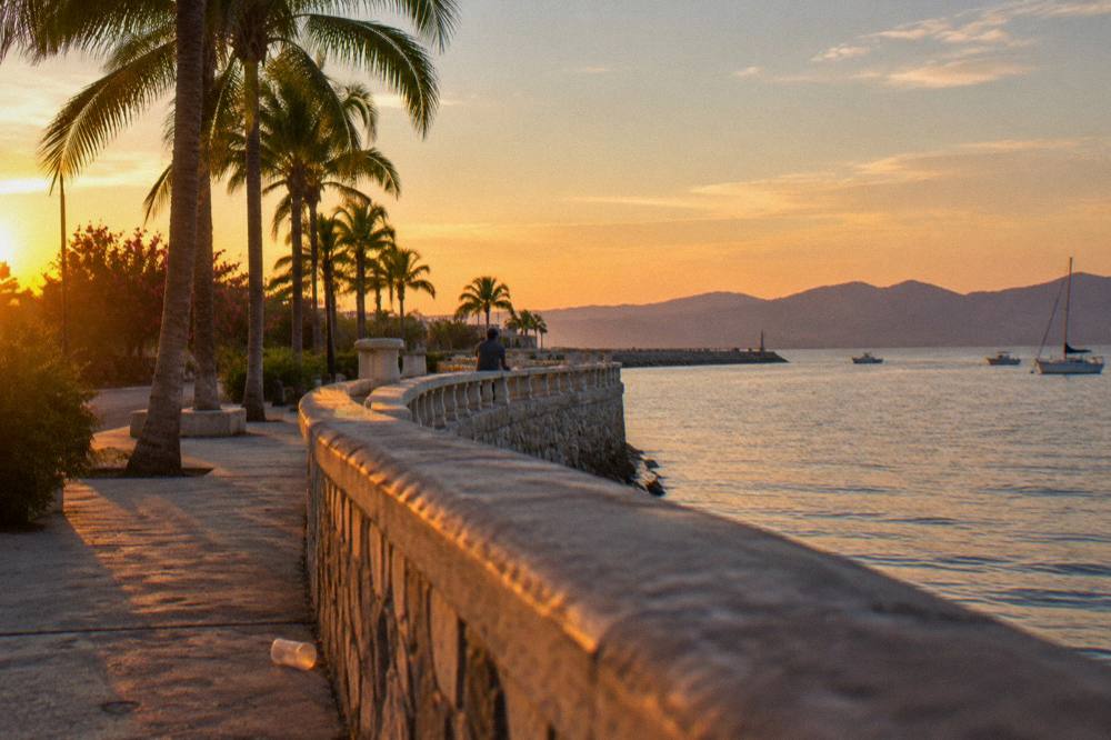 Waterfront promenade of La Paz at sunset with calm bay water beyond