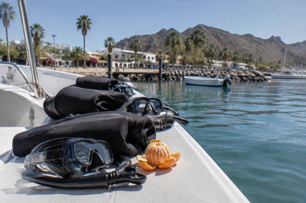 Snorkel masks and wetsuits laid out on a boat bench