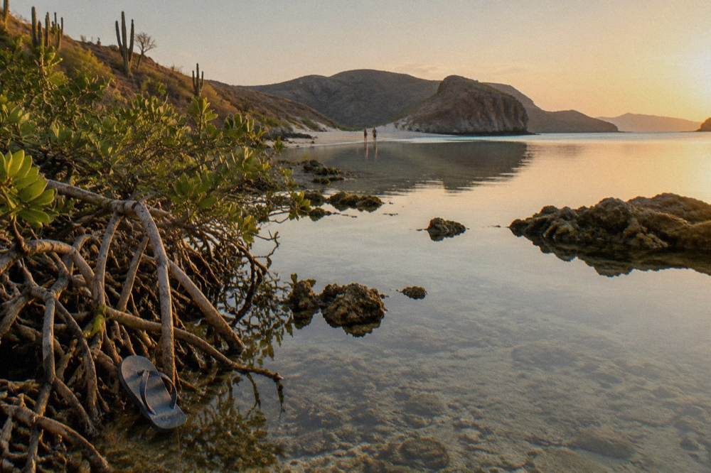 Shallow turquoise water of a protected cove ringed by low desert hills
