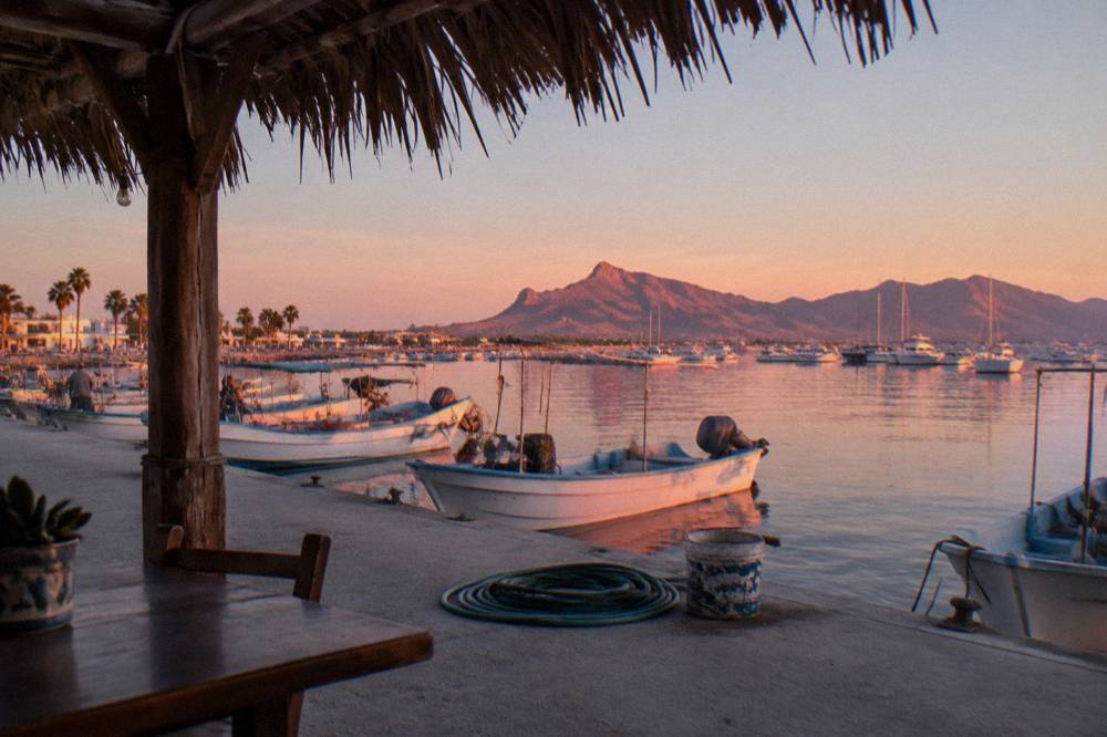 Waterfront promenade at sunrise with moored boats and a long pier