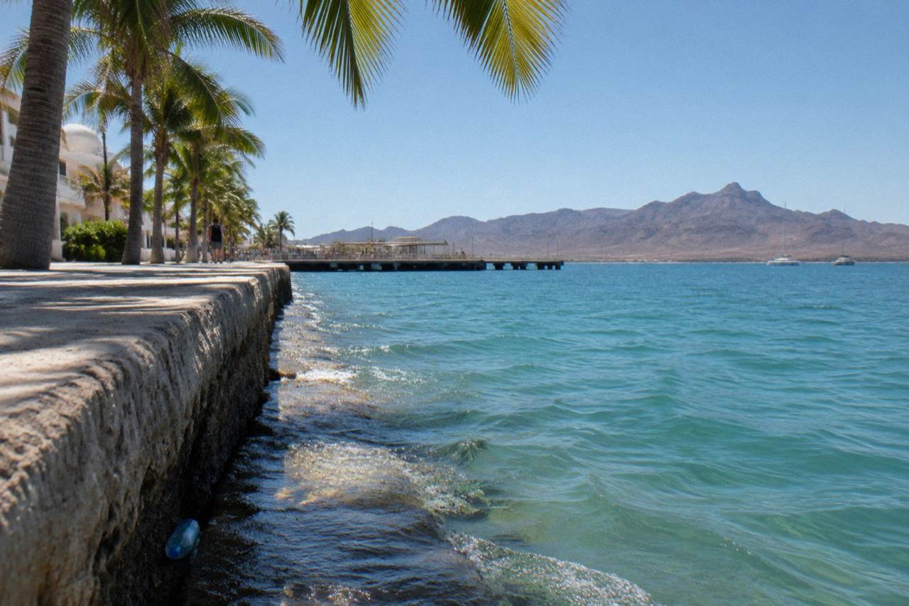 Calm turquoise water of the bay beside the La Paz boardwalk under a clear morning sky