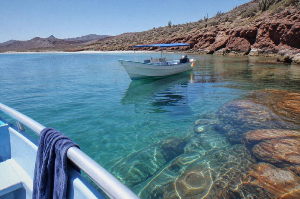Snorkel boat anchored near a rocky point with clear water below