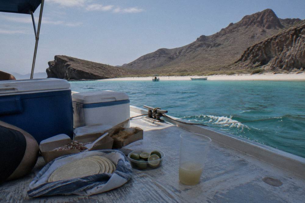 Beach picnic set out on a boat deck with coolers and food boxes