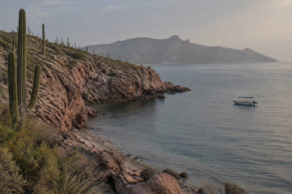 Rocky island coastline with calm water and a small anchored boat
