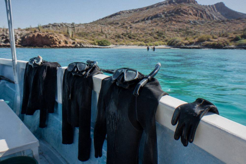 Wetsuits and snorkel masks drying on the rail of a boat at anchor