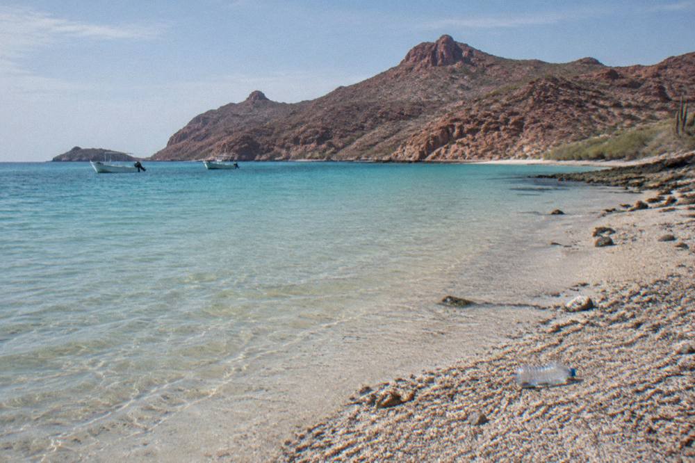 Clear shallow water over sand near Espiritu Santo island with distant pangas moored offshore