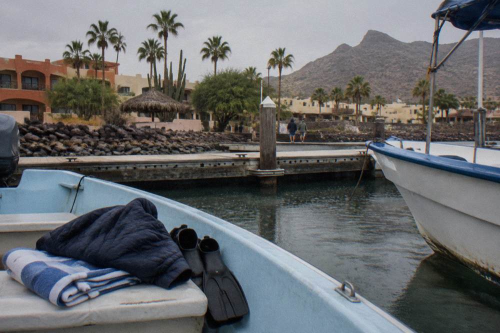 A folded towel and warm jacket resting on a boat seat next to a pair of fins