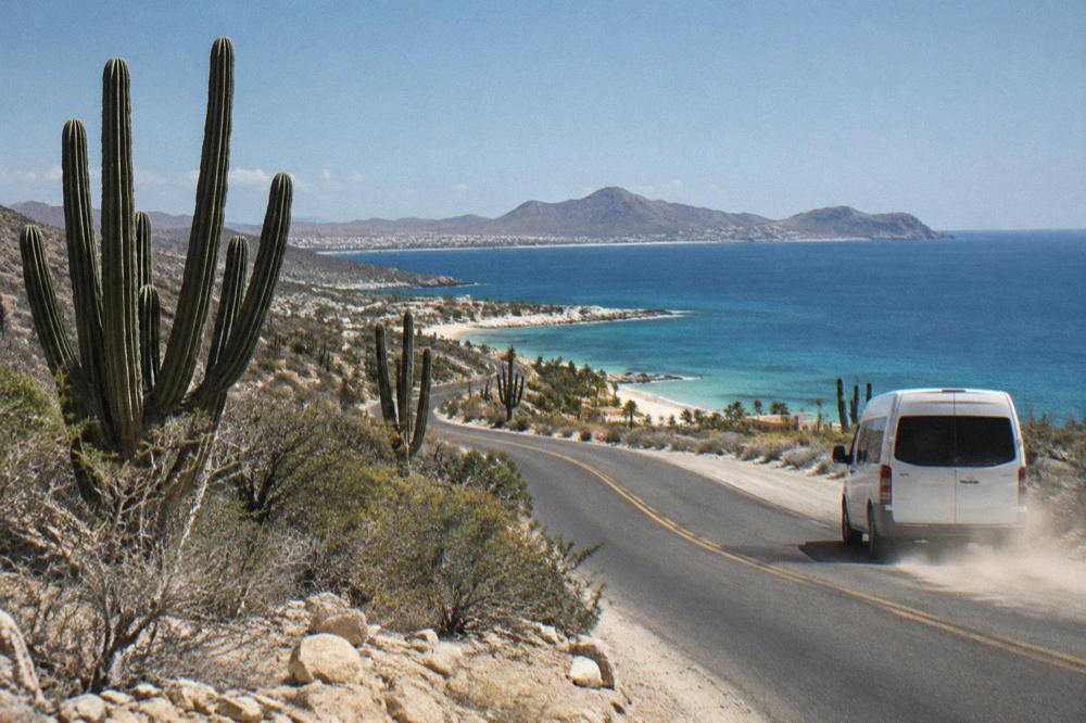A coastal highway curving between desert hills and the sea at morning