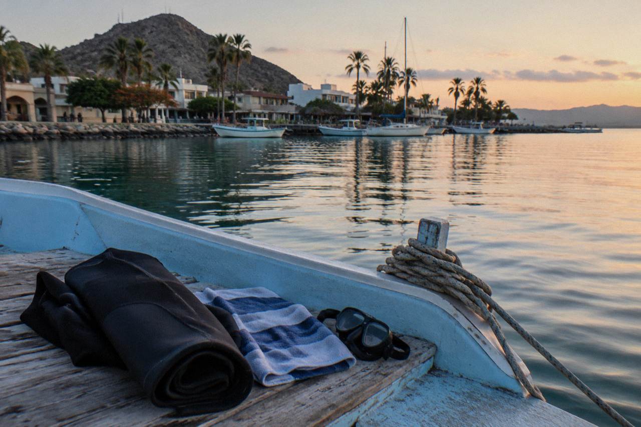 Snorkel gear, wetsuit and towel laid out on a boat deck beside calm blue water