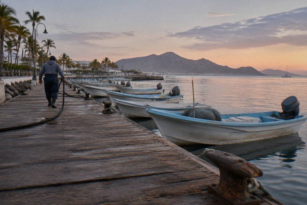 Wooden pier on the La Paz waterfront in early morning light with boats moored along the dock