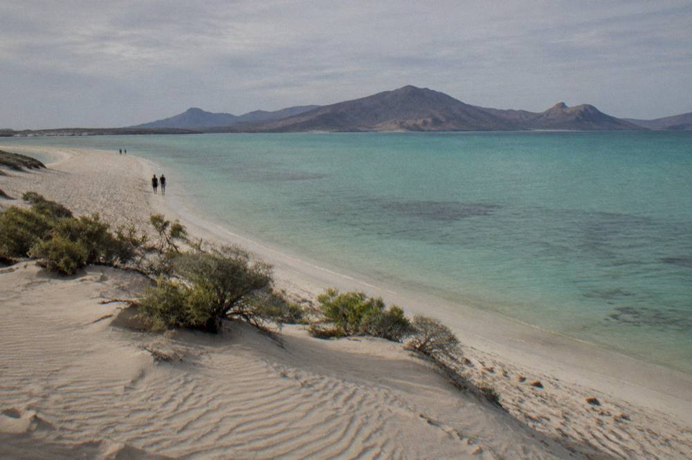 Calm sheltered bay with turquoise shallows and a sandy spit under a wide sky