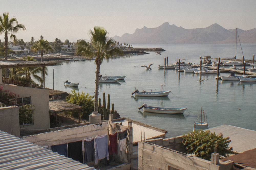 Morning light over La Paz rooftops with fishing boats on the calm bay